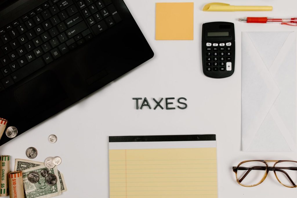 Calculadora, teclado e bloco de notas organizados sobre uma mesa de escritório, associados à gestão tributária.