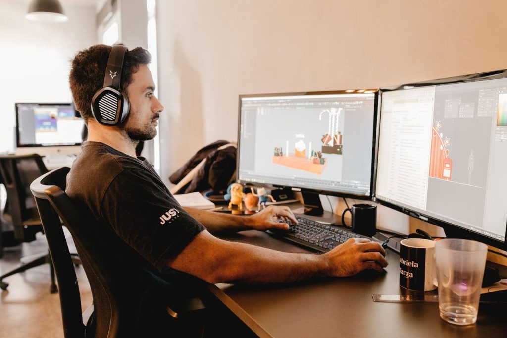 Marco legal dos jogos eletrônicos passa a ter regulamentação no Brasil Profissional usando fones de ouvido trabalha em um computador com dois monitores em um escritório moderno.