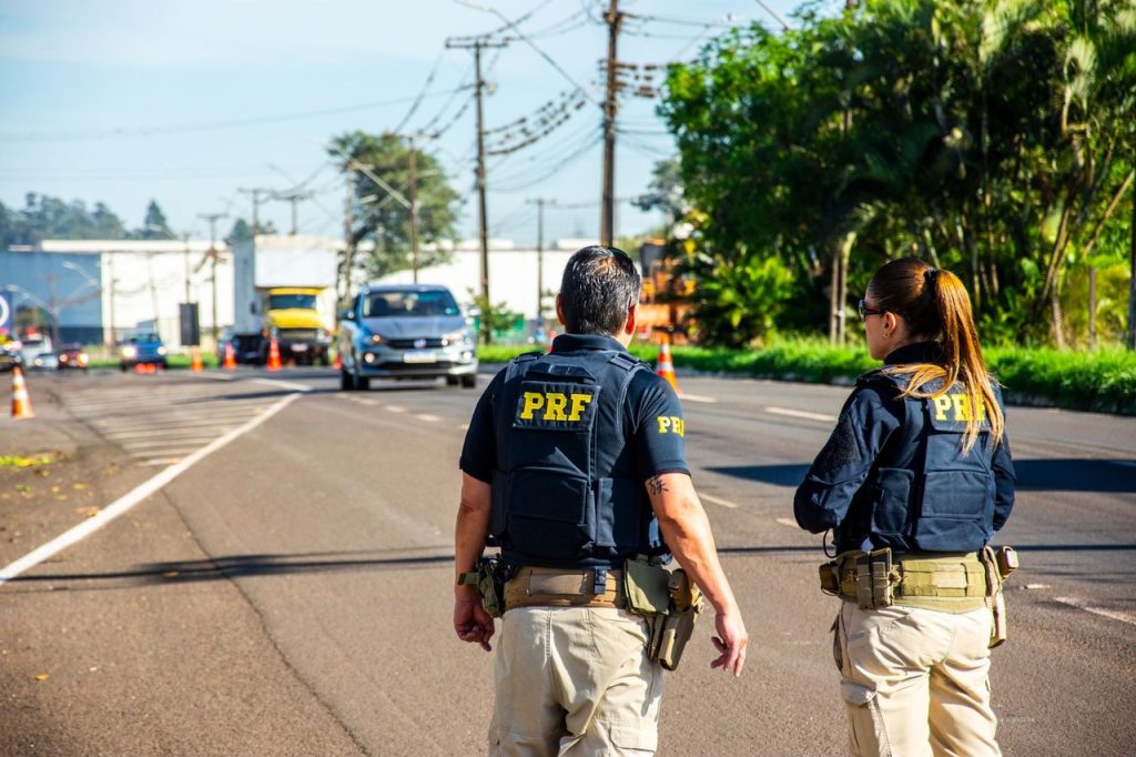 Agentes da Polícia Rodoviária Federal monitoram o trânsito em uma via urbana.
